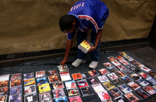 393184 09: A dealer of counterfeit pop and rap music CDs sells his merchandise August 13, 2001 on a street in New York City. Constantly keeping one eye out for the police, these wandering dealers of knock-off CDs, purses, sunglasses, watches and videos can be found by the dozens in any of the tourist districts of New York City. (Photo by Spencer Platt/Getty Images)
